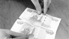 Фальшивая (вверху) и настоящая купюры в руках оперативников.