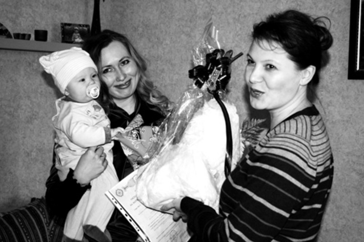 Мама Анна и Арсений Борисовы принимают сертификат, подарки и поздравления.