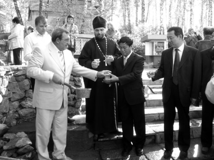 Китайскую делегацию угощают водой из святого источника.