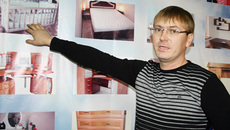 Сергей Седлецкий демонстрирует ассортимент своих товаров, запечатленный на специальном стенде.