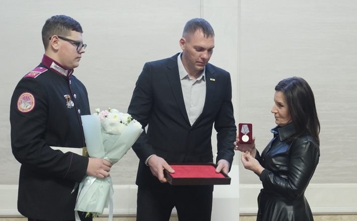 Участники поисковой экспедиции передают Ларисе Новосад медаль «За отвагу», которую ее дед потерял на полях сражений Великой Отечественной войны. Фото: nso.ru